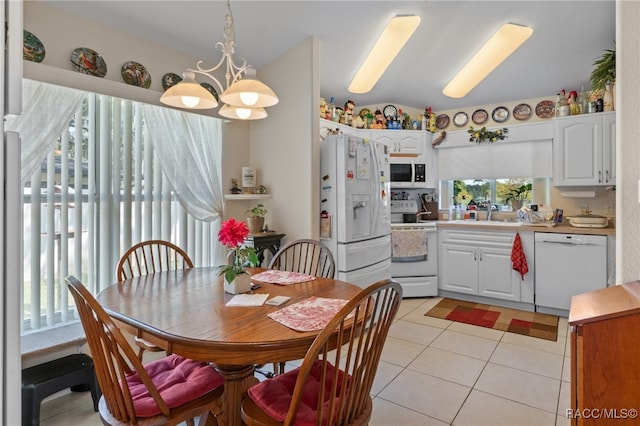 kitchen with white appliances, white cabinets, hanging light fixtures, light tile patterned floors, and a notable chandelier