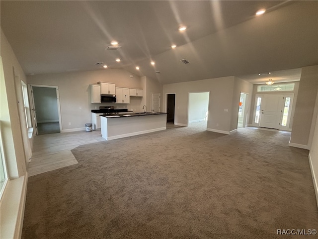 kitchen with sink, a kitchen island with sink, light carpet, and white cabinets