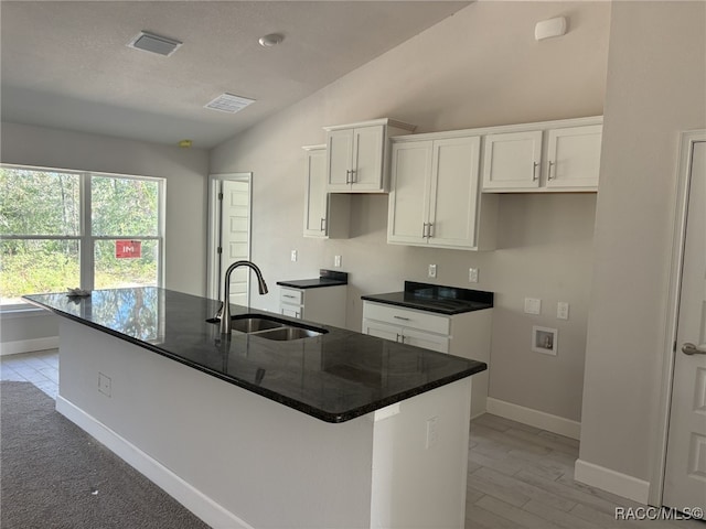 kitchen featuring a center island with sink, white cabinetry, and sink