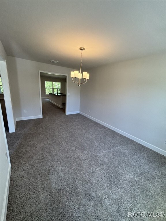 2400 W Tall Oaks Dr, Beverly Hills, FL 34465 - spare room featuring a chandelier, dark carpet, and baseboards