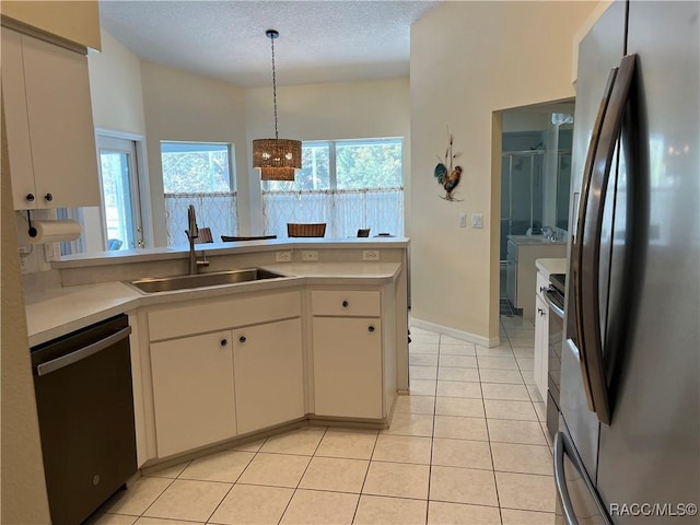 kitchen featuring a sink, white cabinetry, light countertops, freestanding refrigerator, and dishwasher