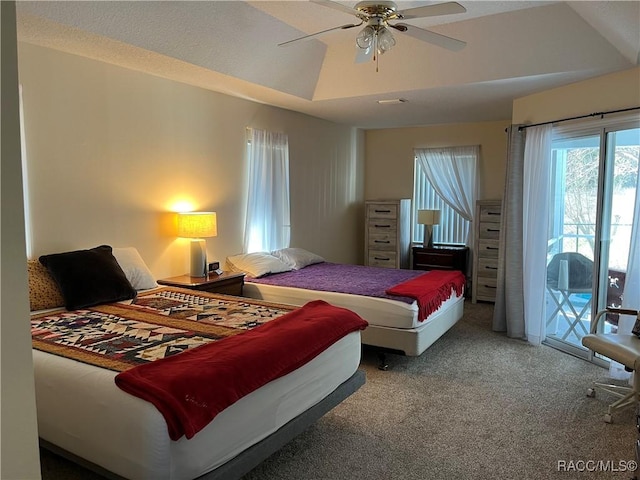 bedroom featuring carpet, lofted ceiling, a raised ceiling, a ceiling fan, and access to outside