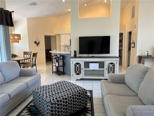 living room with high vaulted ceiling, light tile patterned flooring, and visible vents