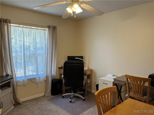 carpeted office featuring a ceiling fan and baseboards