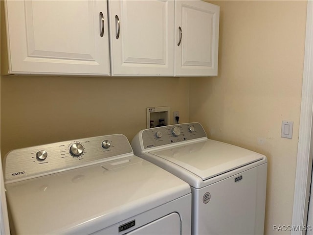 clothes washing area featuring washing machine and dryer and cabinet space