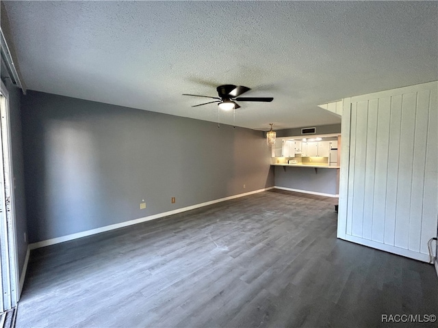 unfurnished living room with a textured ceiling, dark hardwood / wood-style floors, and ceiling fan