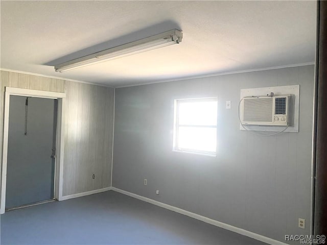 empty room featuring concrete floors, crown molding, a wall mounted AC, and wooden walls