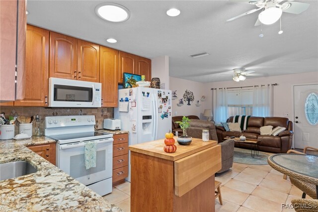 kitchen featuring tasteful backsplash, visible vents, open floor plan, light stone countertops, and white appliances