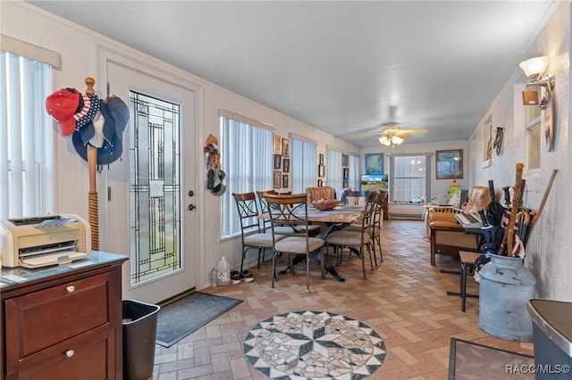 dining space featuring ceiling fan, brick floor, and plenty of natural light