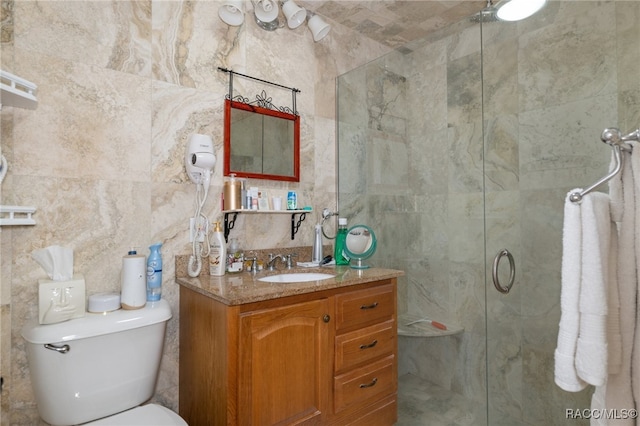 bathroom with toilet, a stall shower, tile walls, and vanity