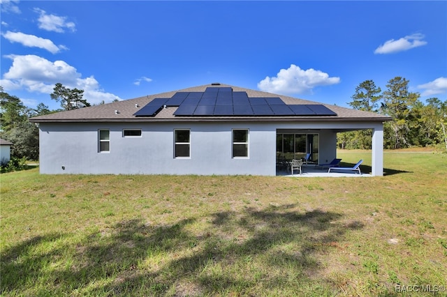 rear view of property featuring a lawn, a patio, and solar panels