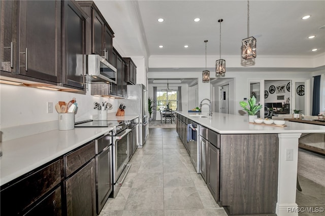 kitchen with ornamental molding, pendant lighting, stainless steel appliances, and a spacious island