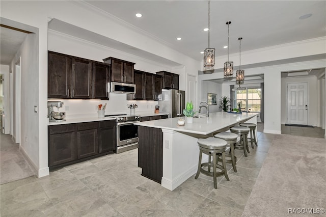 kitchen with sink, stainless steel appliances, decorative light fixtures, a kitchen island with sink, and a breakfast bar