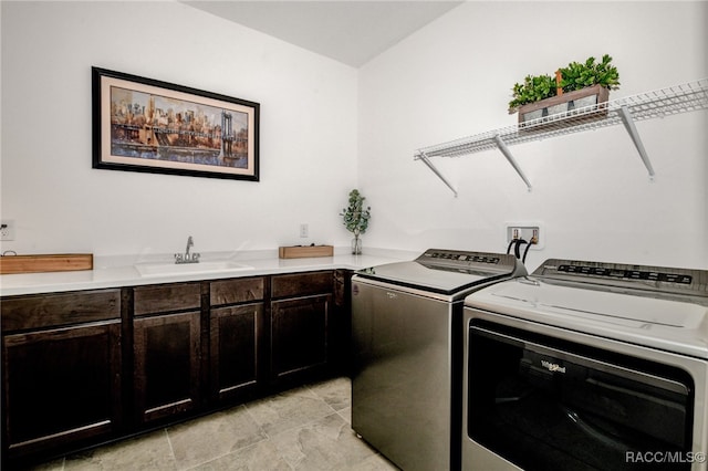 clothes washing area with cabinets, washing machine and dryer, and sink