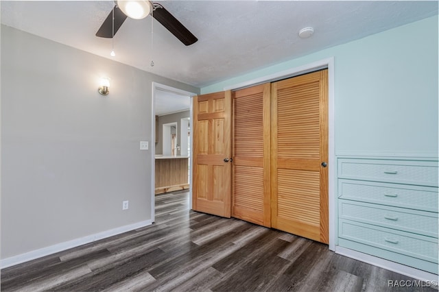 unfurnished bedroom with a textured ceiling, dark hardwood / wood-style flooring, a closet, and ceiling fan