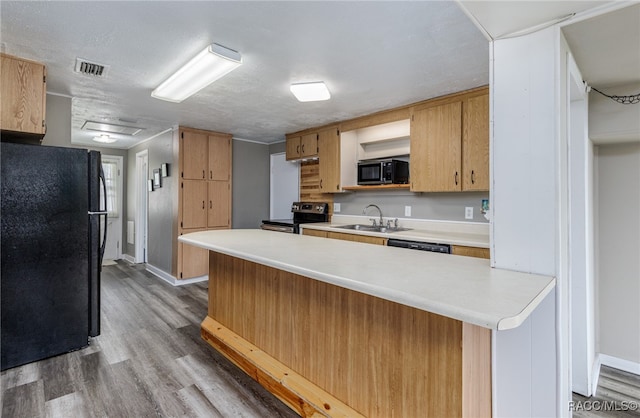 kitchen with kitchen peninsula, a textured ceiling, sink, black appliances, and light hardwood / wood-style flooring