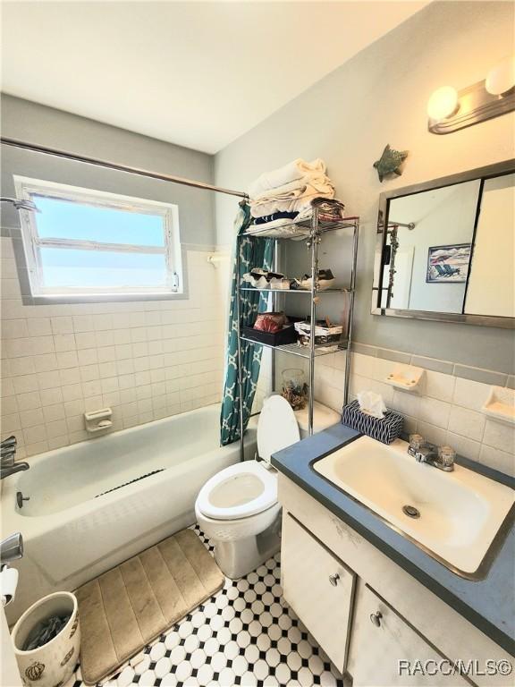 full bathroom featuring vanity, wood finished floors, shower / bath combo with shower curtain, tile walls, and toilet