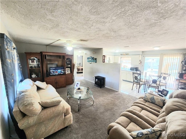 living room featuring baseboards, a textured ceiling, a ceiling fan, and carpet floors