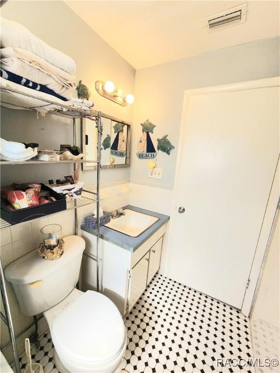 bathroom featuring visible vents, toilet, and vanity