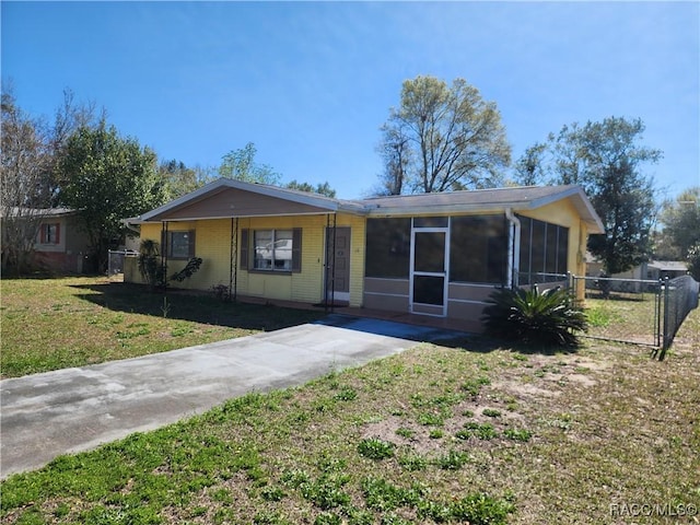 ranch-style house with a front yard, fence, brick siding, and a sunroom