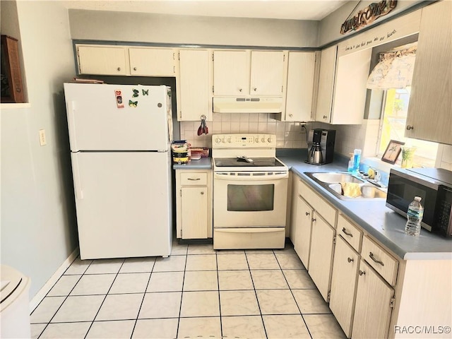 kitchen featuring backsplash, under cabinet range hood, light tile patterned floors, white appliances, and a sink