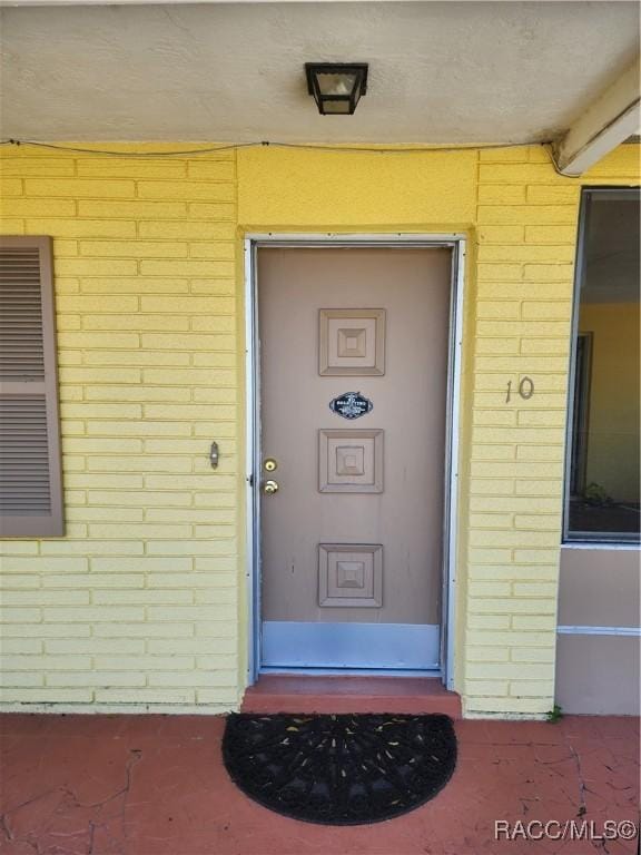 view of exterior entry featuring brick siding