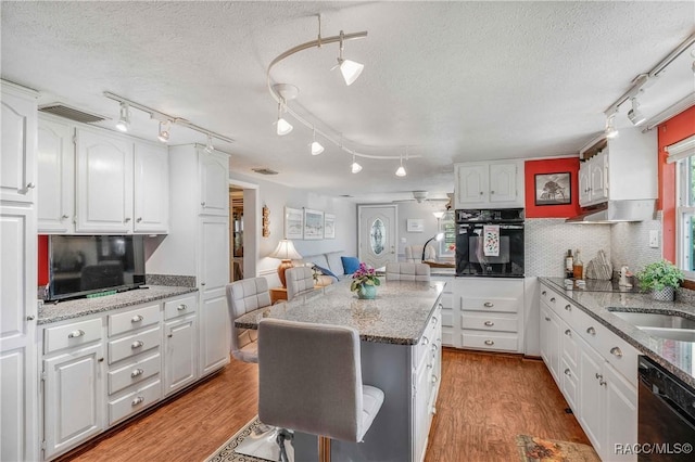 13465 W Hillbilly Ln, Crystal River, FL 34429 - kitchen with black appliances, track lighting, a textured ceiling, white cabinetry, and light wood-style flooring