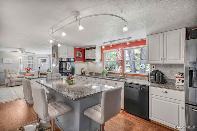 13465 W Hillbilly Ln, Crystal River, FL 34429 - kitchen with black appliances, a sink, white cabinetry, a kitchen bar, and light wood finished floors