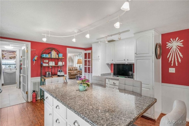 13465 W Hillbilly Ln, Crystal River, FL 34429 - kitchen with wainscoting, a textured ceiling, white cabinetry, dark stone counters, and a center island