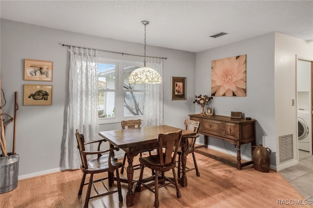 dining area with washer / dryer, light wood-type flooring, and a textured ceiling