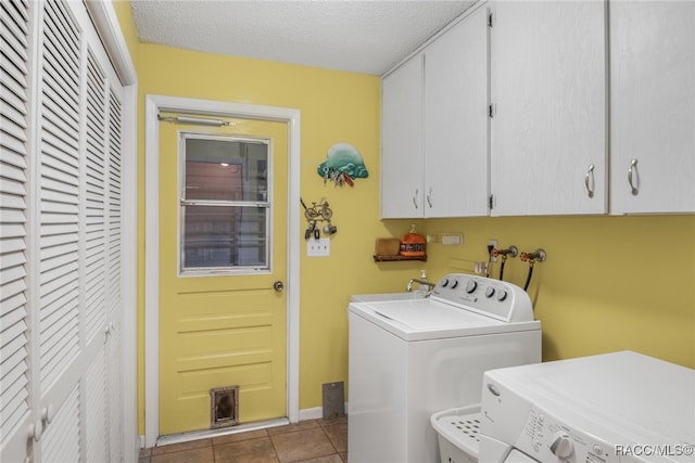 washroom with cabinets, sink, independent washer and dryer, a textured ceiling, and light tile patterned flooring