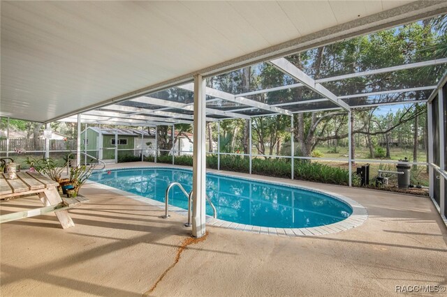 view of swimming pool featuring a lanai, a patio area, and a shed