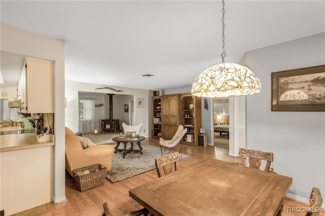 dining room with light hardwood / wood-style flooring, a wood stove, and plenty of natural light