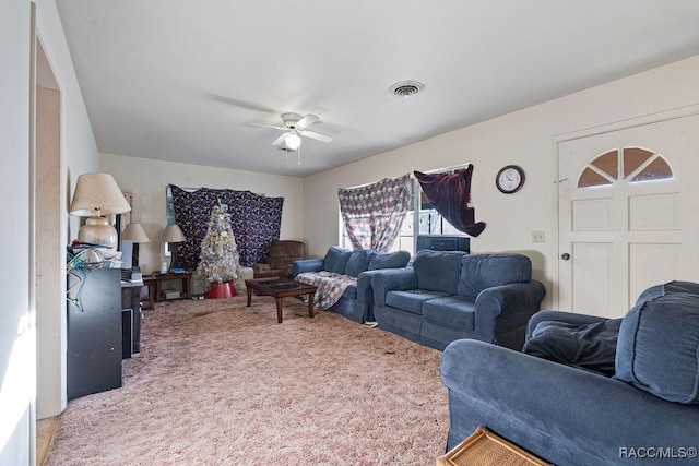 living room featuring a ceiling fan, visible vents, and light colored carpet