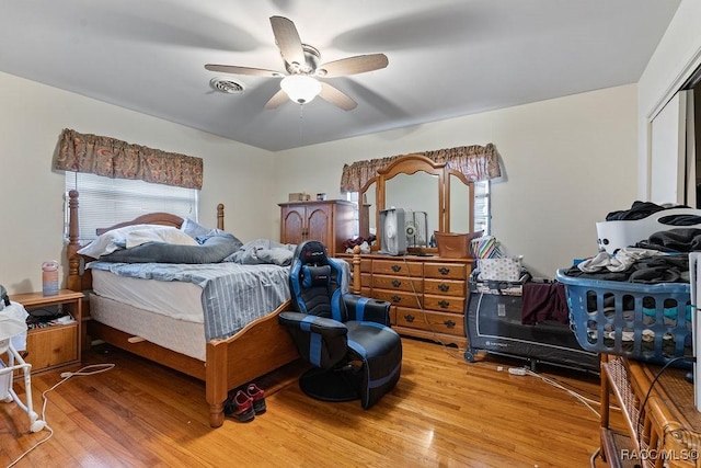 bedroom with a closet, light wood-type flooring, visible vents, and a ceiling fan