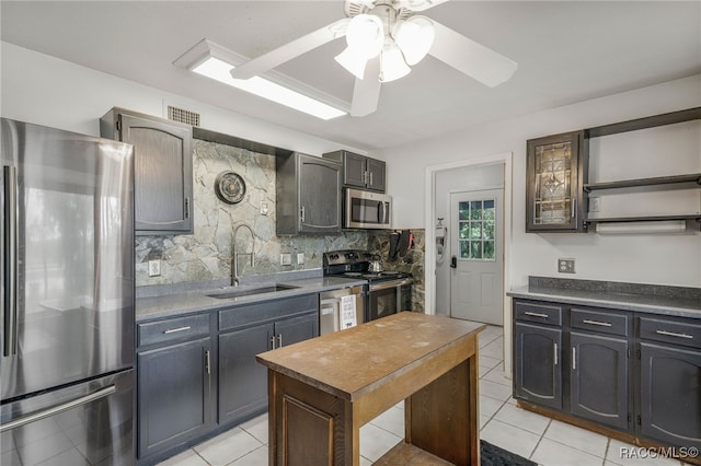 kitchen with open shelves, decorative backsplash, a sink, light tile patterned floors, and stainless steel appliances