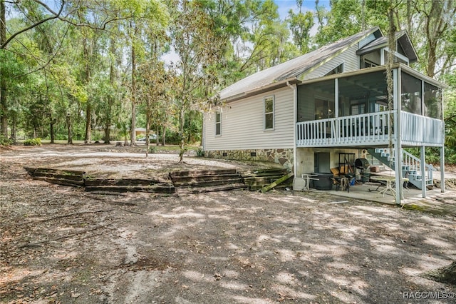 view of side of property with stairs, a patio, and a sunroom