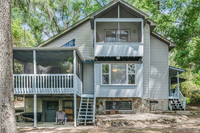 rear view of house with a patio, stairs, and a sunroom