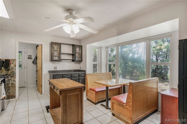interior space featuring glass insert cabinets, light tile patterned floors, ceiling fan, and a center island