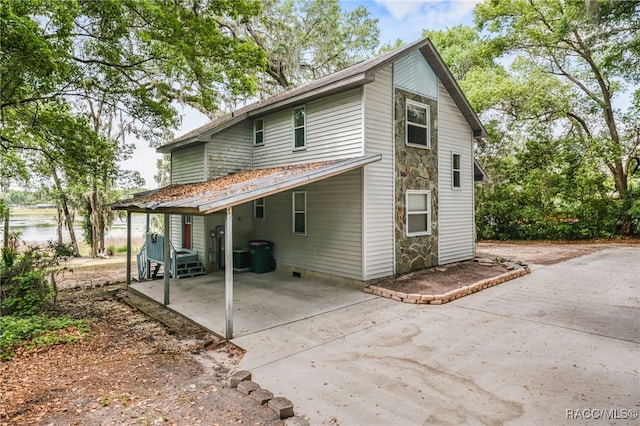 back of house featuring concrete driveway and a carport
