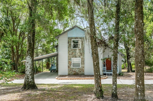 view of front of home with driveway, stone siding, and an attached carport
