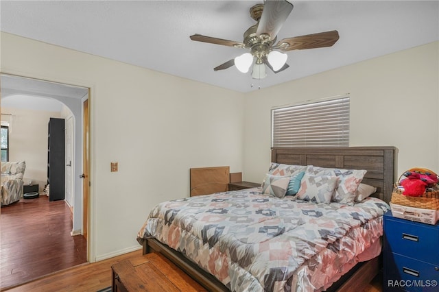 bedroom with arched walkways, baseboards, a ceiling fan, and wood finished floors