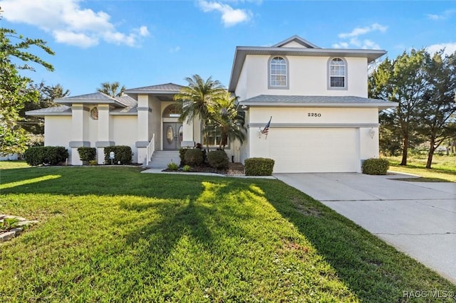 view of front of house featuring a front yard, driveway, an attached garage, and stucco siding