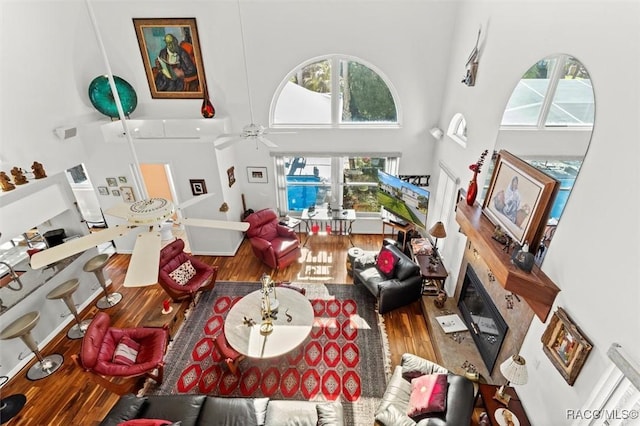 living area with a high ceiling, a ceiling fan, and wood finished floors