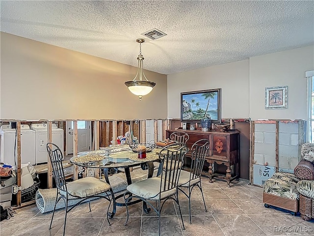dining room with visible vents, a textured ceiling, and washer / dryer