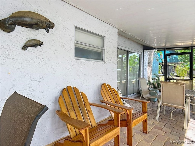 sunroom / solarium with a textured wall and stone tile flooring
