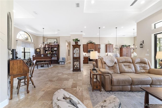 living room featuring crown molding, a raised ceiling, and a notable chandelier