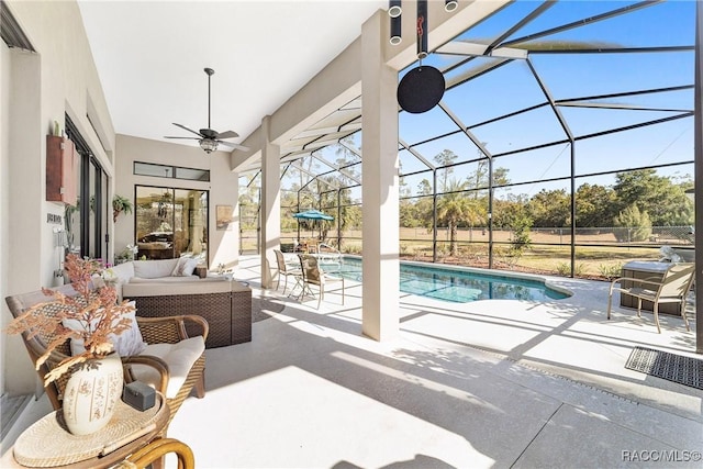 view of pool with an outdoor living space, a patio area, ceiling fan, and glass enclosure