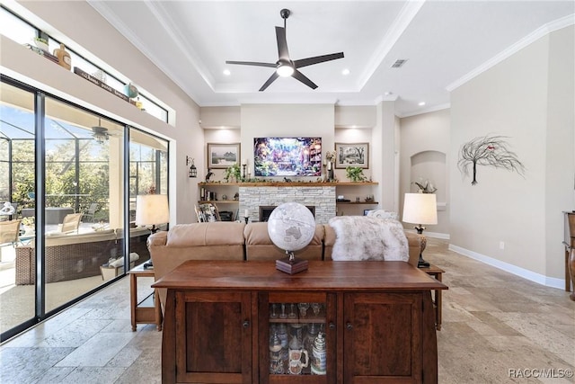 bedroom featuring ceiling fan, a fireplace, ornamental molding, and a tray ceiling