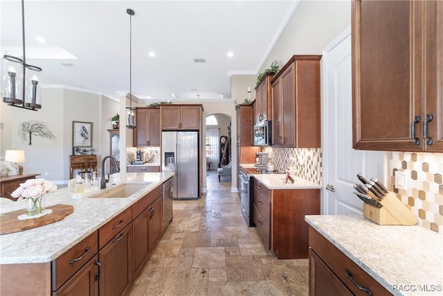 kitchen with sink, appliances with stainless steel finishes, pendant lighting, light stone countertops, and backsplash